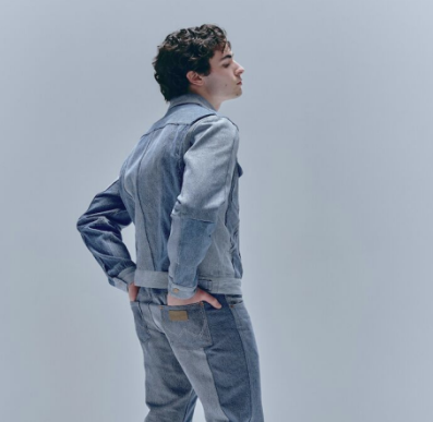 	
Young man with curly hair in an upcycled denim jacket manufactured by Beyond Remade for the global fashion brand Wrangler.