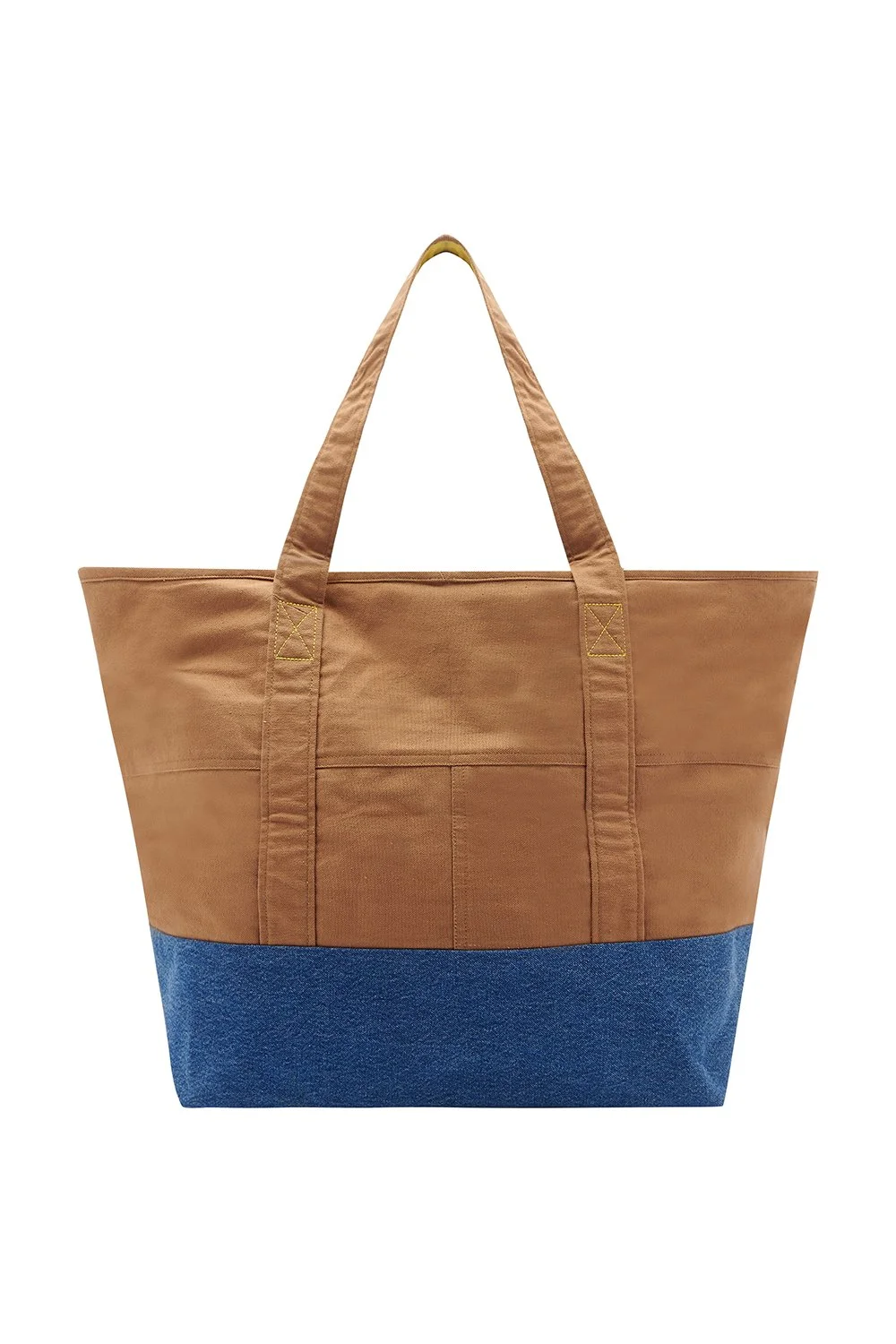 A large tote bag with tan fabric on the upper part and blue denim on the bottom, and two tan handles.