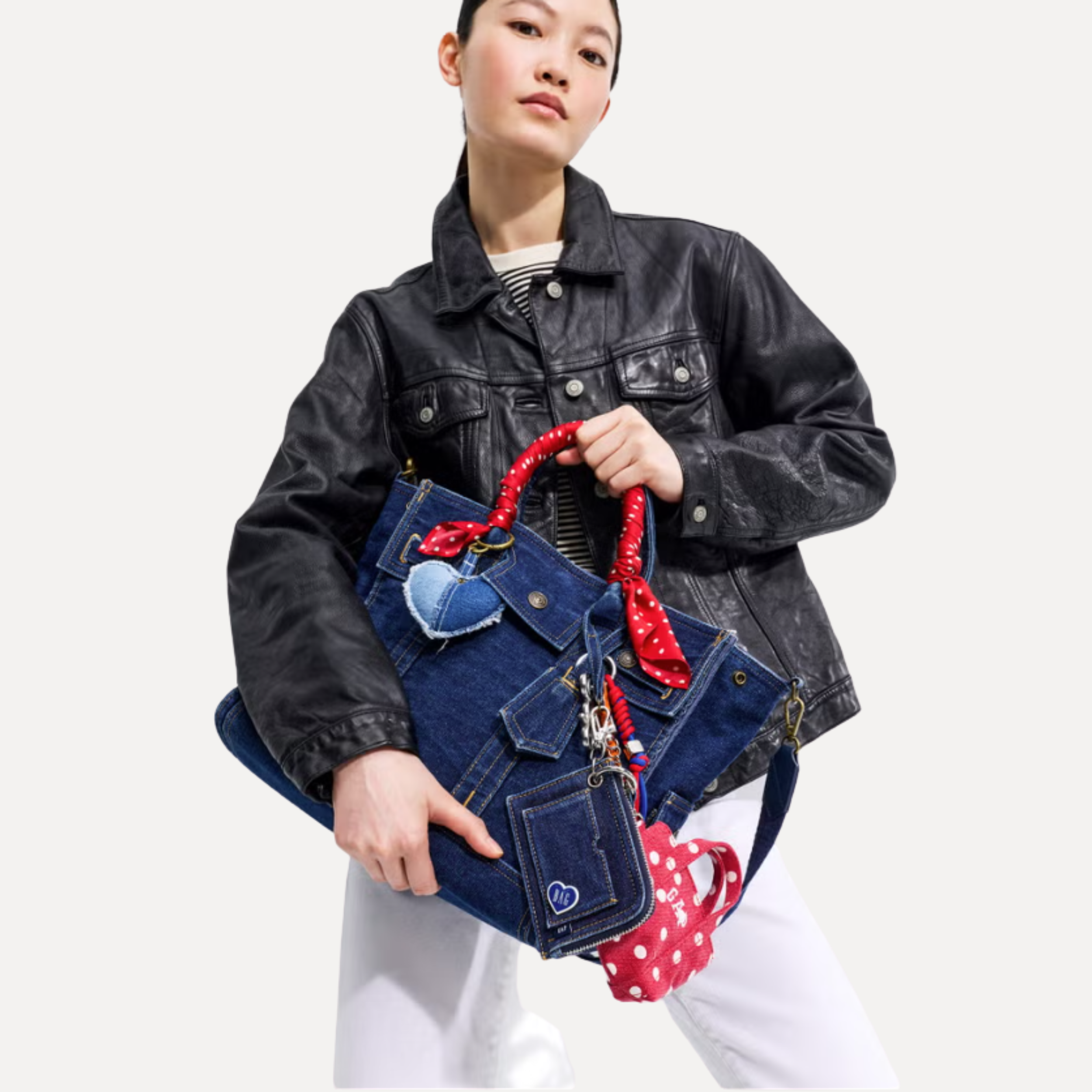 Model carrying a dark denim Gap Five Pocket Tote from the GapBag Collection, featured in the Beyond Remade by Bank & Vogue case study, styled with a red polka dot scarf and a patchwork denim heart charm.