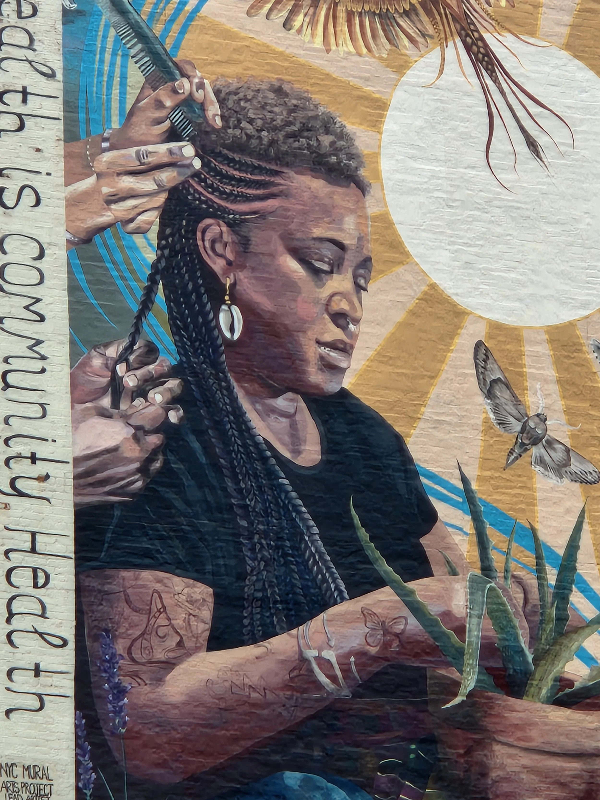A mural of a woman braiding her hair, with a large sun, butterflies, a bee, and plants in the background.