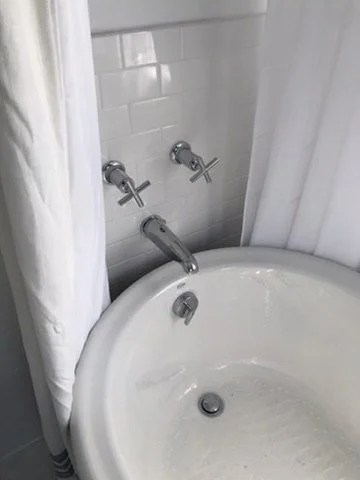 Bathroom sink with two wall-mounted faucets and a shower curtain.