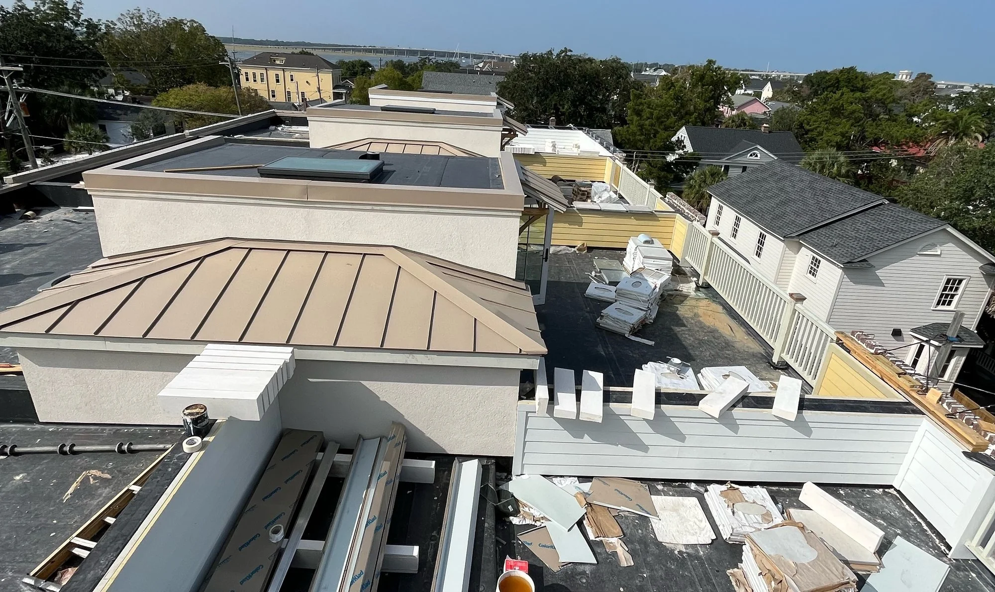 Rooftop view of a copper-tone standing-seam metal roof and flat roof with skylight