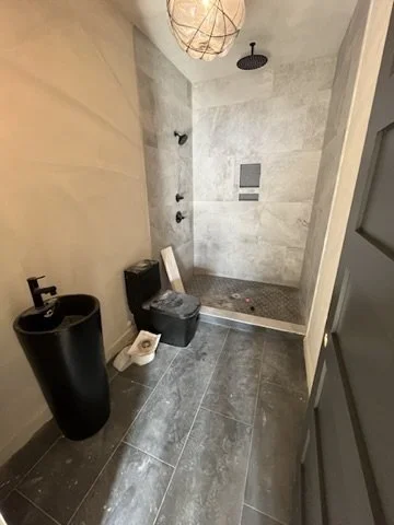 Modern bathroom with a black sink, a toilet, and a walk-in shower with a rain showerhead.
