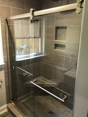 Inside a shower with glass sliding doors, tiled walls, and built-in wall niches.