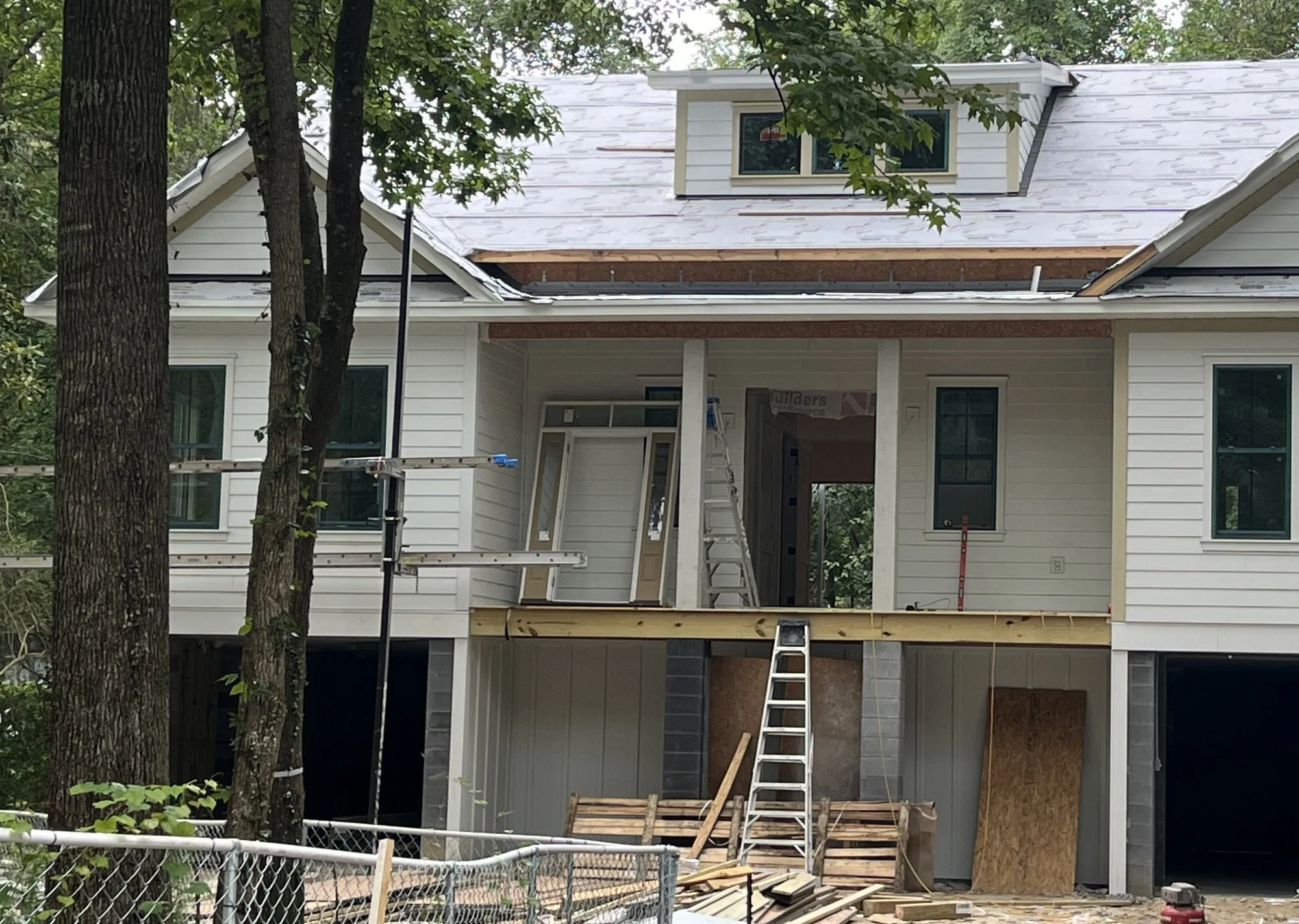 Raised home under construction with roof underlayment and new siding