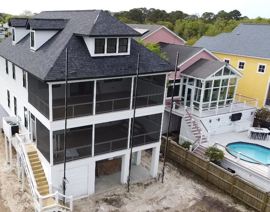 Aerial view of a three-story coastal home with a new charcoal shingle roof and dormers