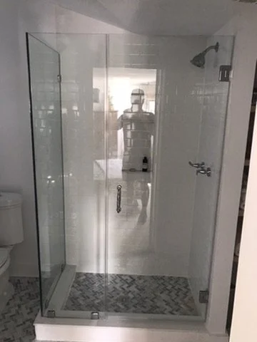 Bathroom shower with glass enclosure, showerhead, and tile floor.