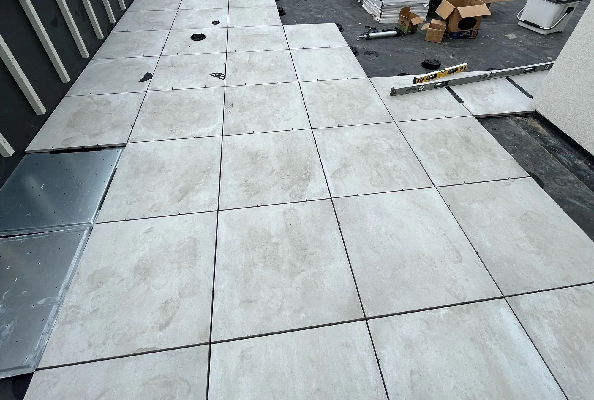 Porcelain paver rooftop terrace being installed over a flat roof membrane