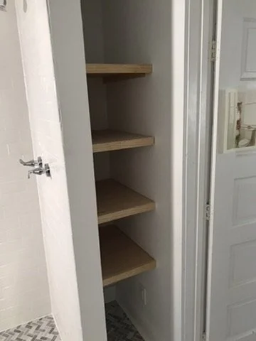 Empty closet with four wooden shelves inside