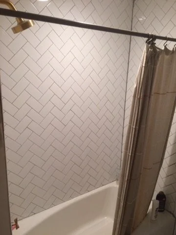 01-finished-bathroom-tub-and-herringbone-tile.jpeg