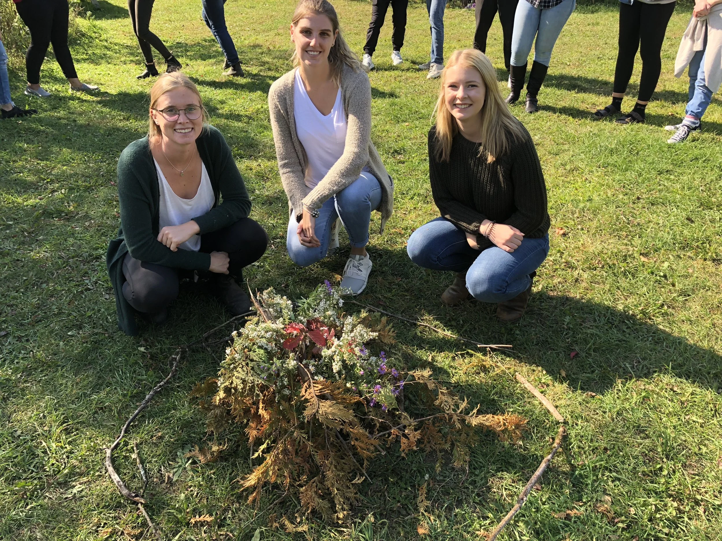 Three educators taking part in a hands-on outdoor learning activity using flowers and natural materials.