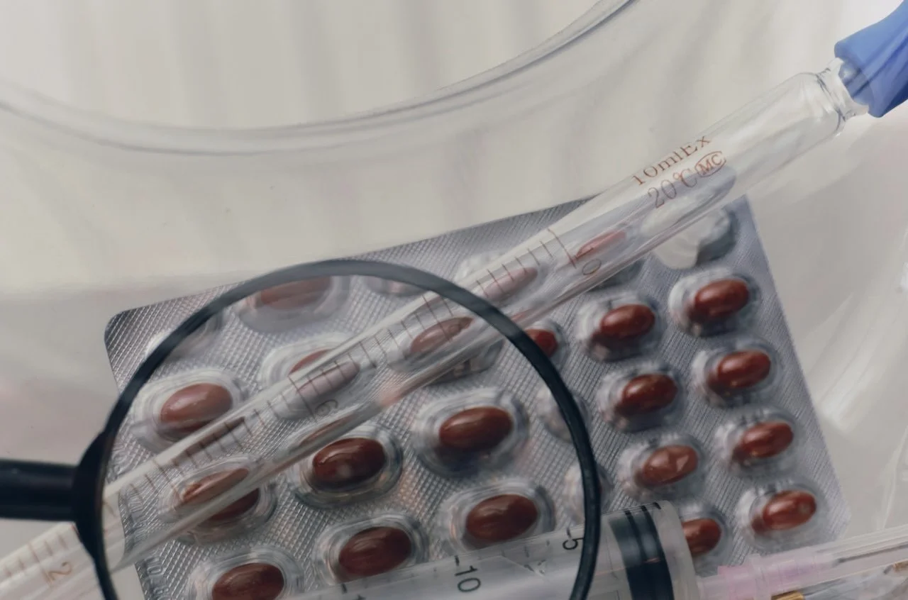 Close-up view of pill packet and syringe on white cloth surface