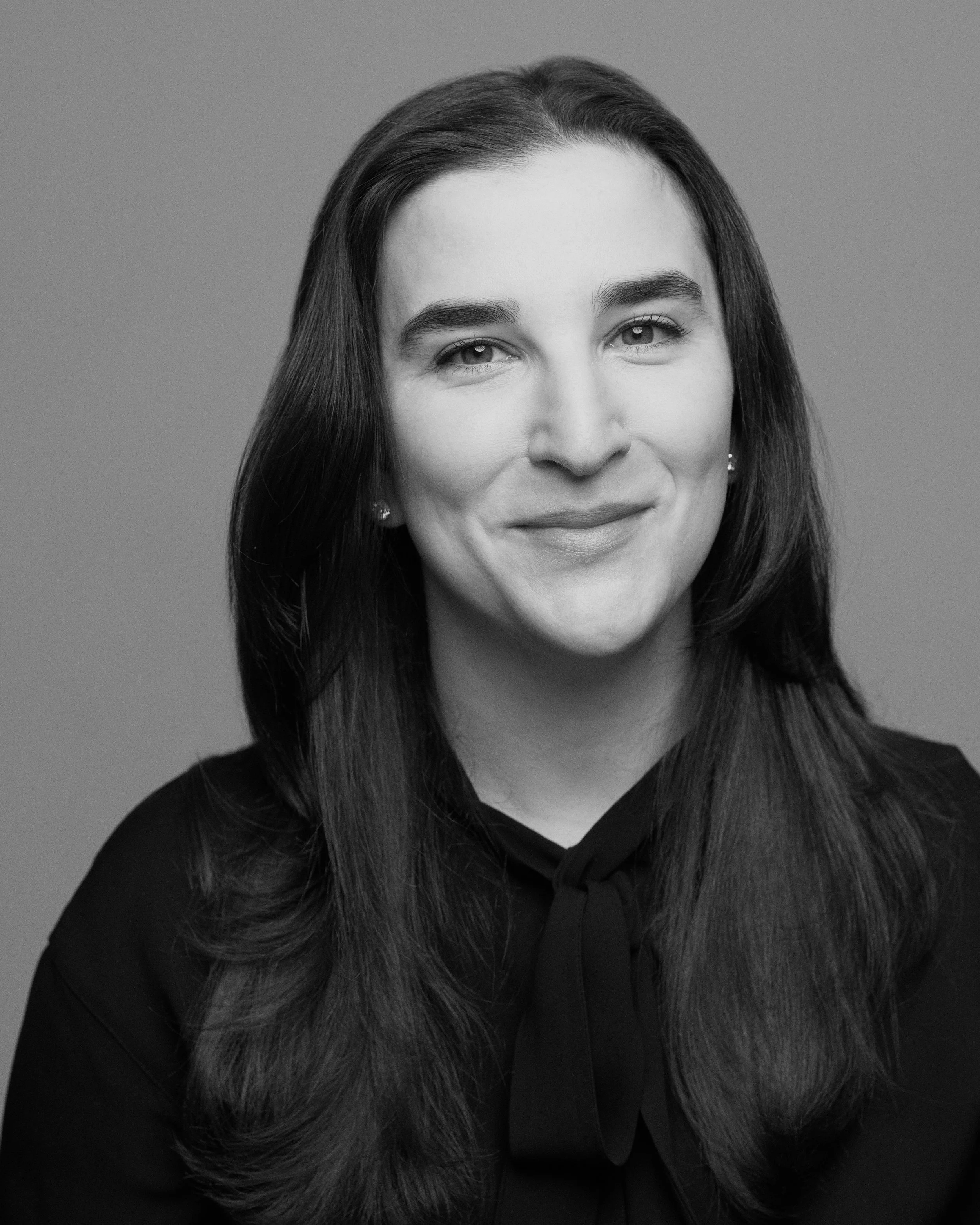 Headshot of woman in dark blouse smiling at camera