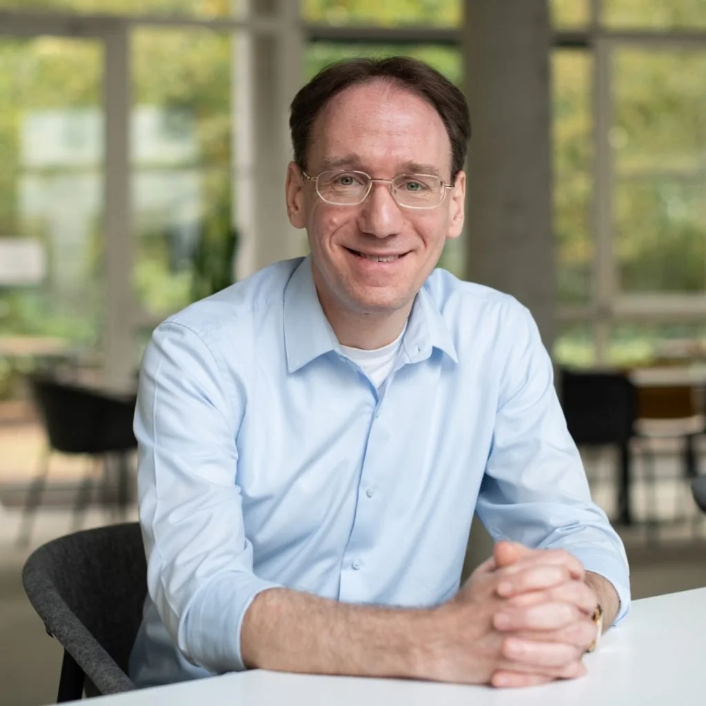 Headshot of man sitting at table with hands clasped