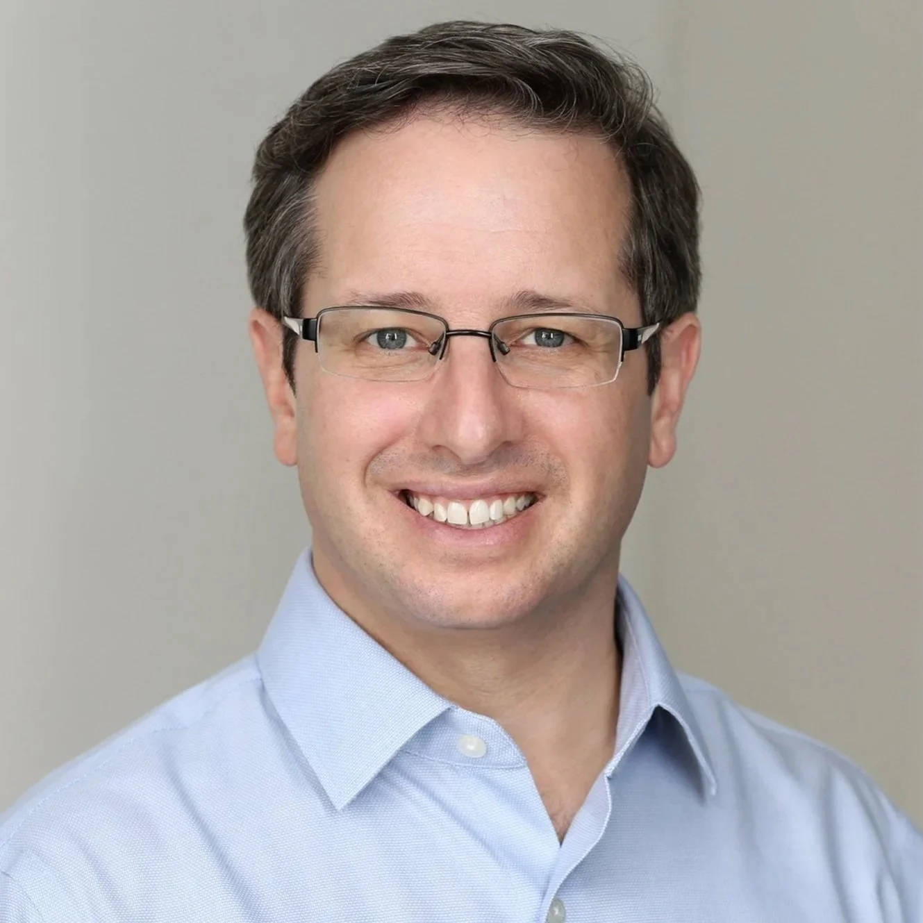 Headshot of man in blue shirt smiling at camera