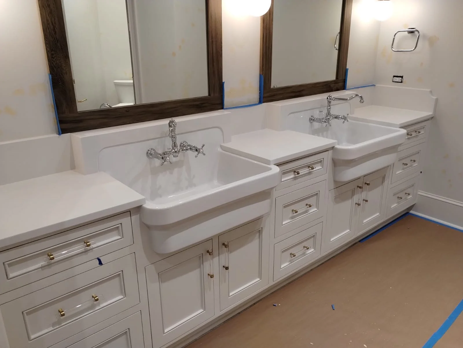 Bathroom vanity with three sinks, backsplash, and mirrors, under renovation, with blue painter's tape and no fixtures on the wall.