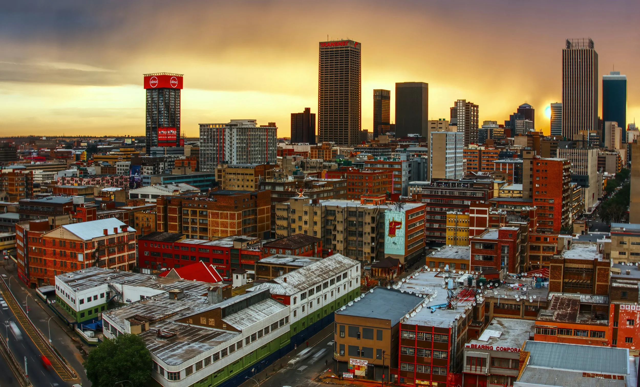City skyline at sunset with tall buildings and a partly cloudy sky.