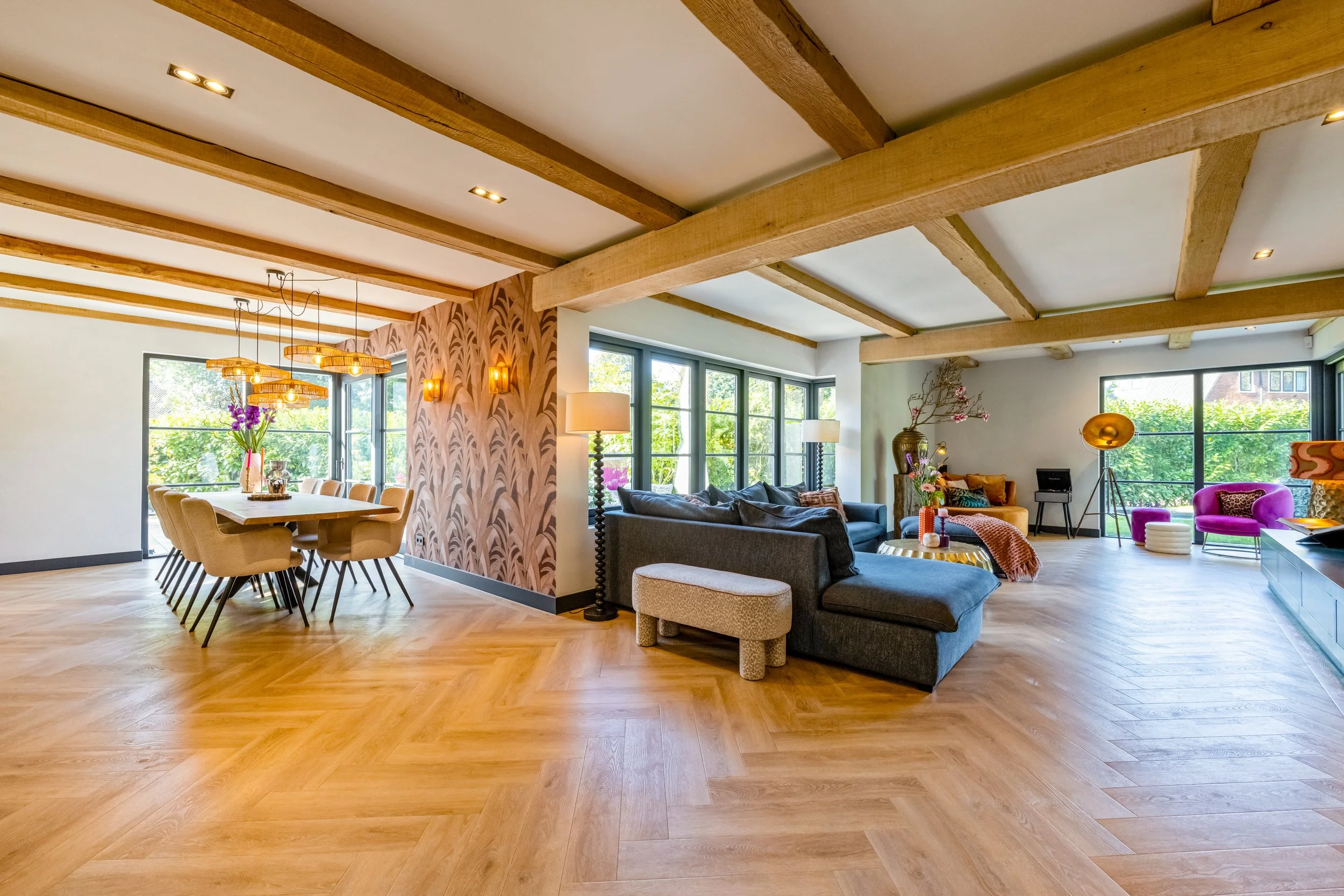 Ruimtelijk en gezellig woon- en eetkamer met houten vloeren, grote ramen, moderne meubels en decoraties.