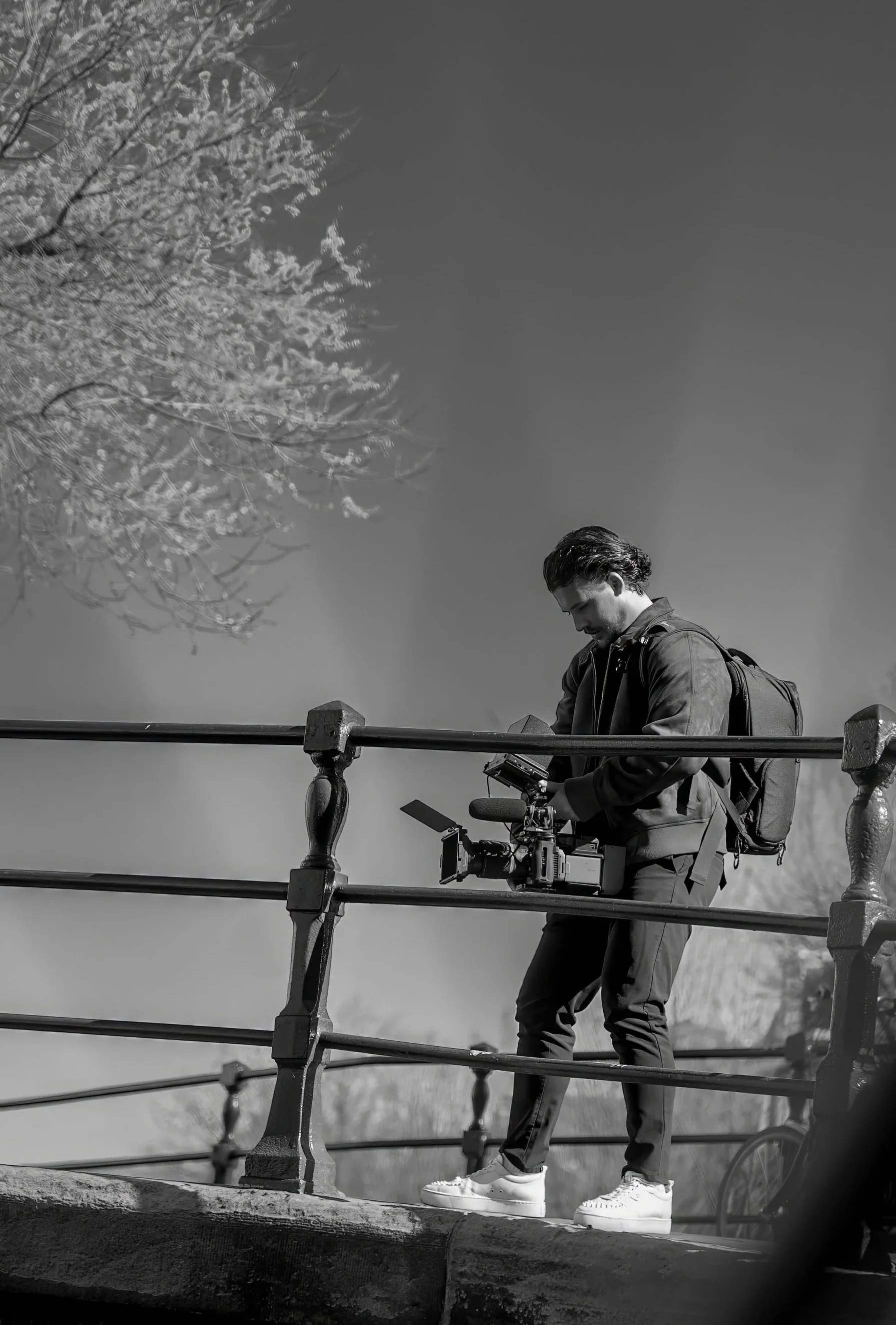 Man met een rugzak die op een brug staat en een camera vasthoudt