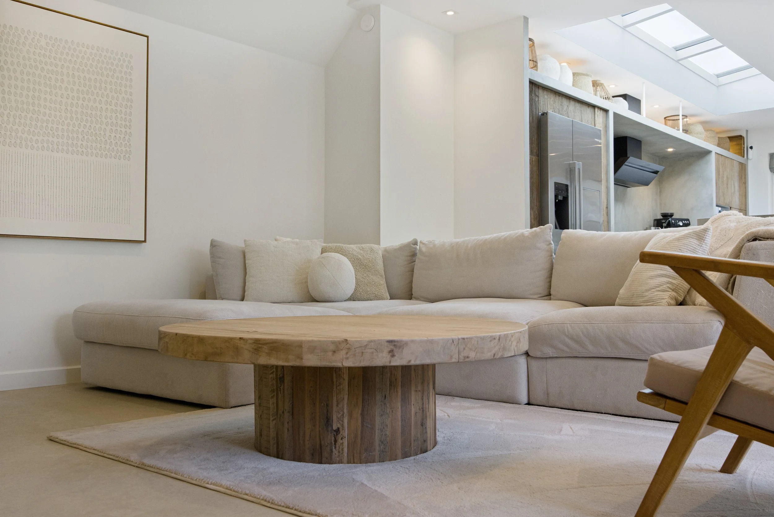 Woonkamer met een beige bank, een houten salontafel en een beige vloerkleed.