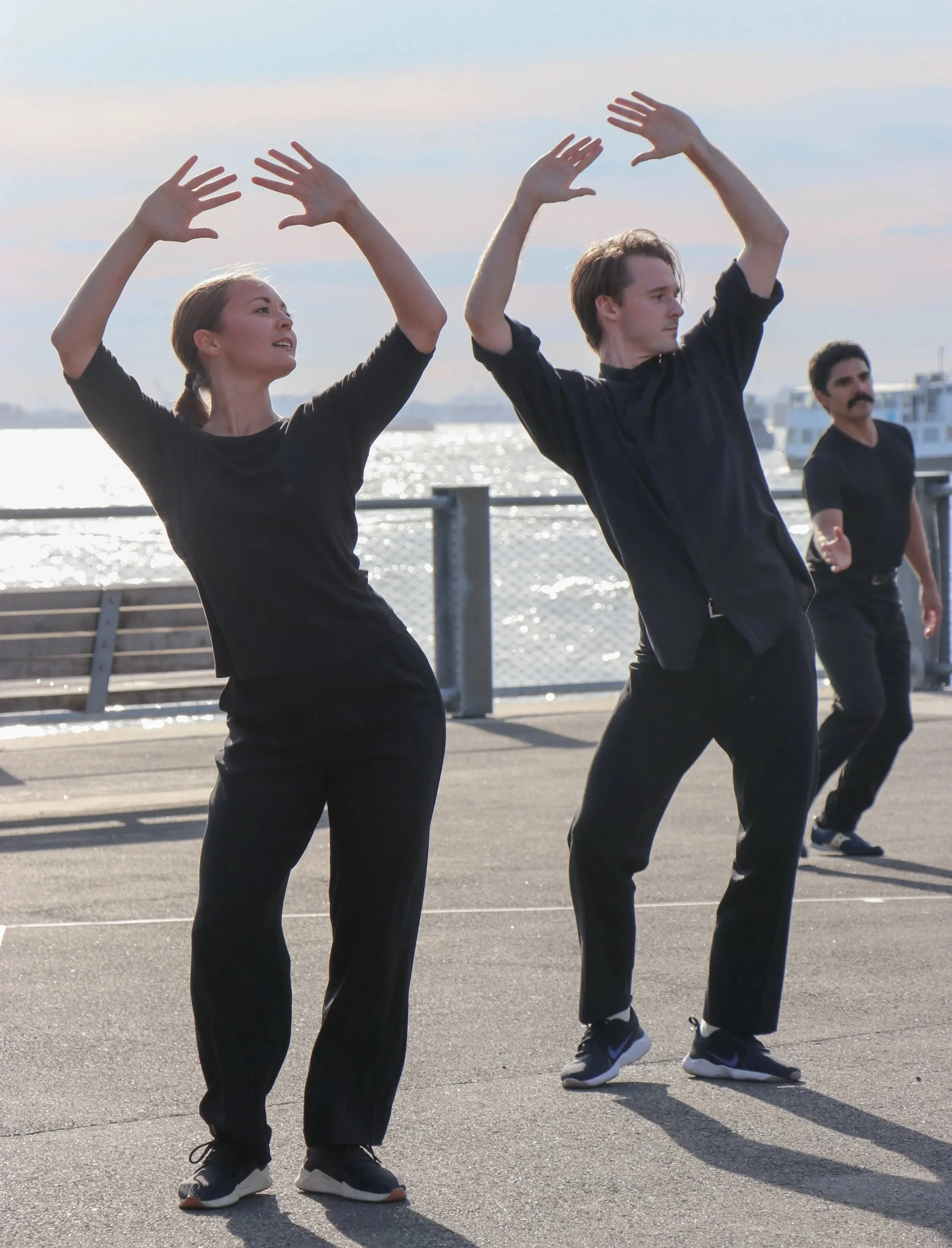 People performing a dance routine outdoors near a waterfront during daytime.