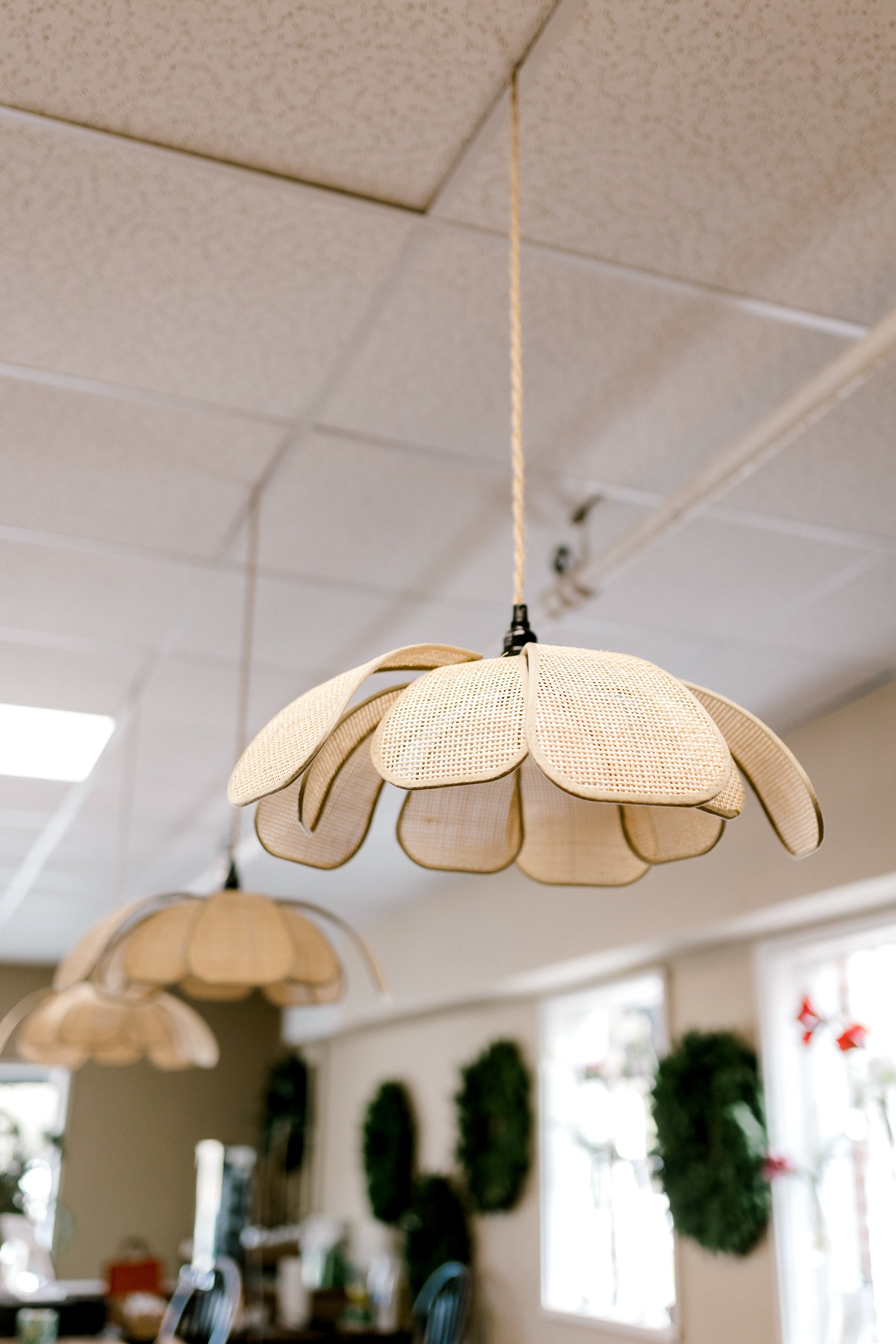 Two pendant lamps with flower petal-like shades hanging from a ceiling in a room decorated for Christmas.