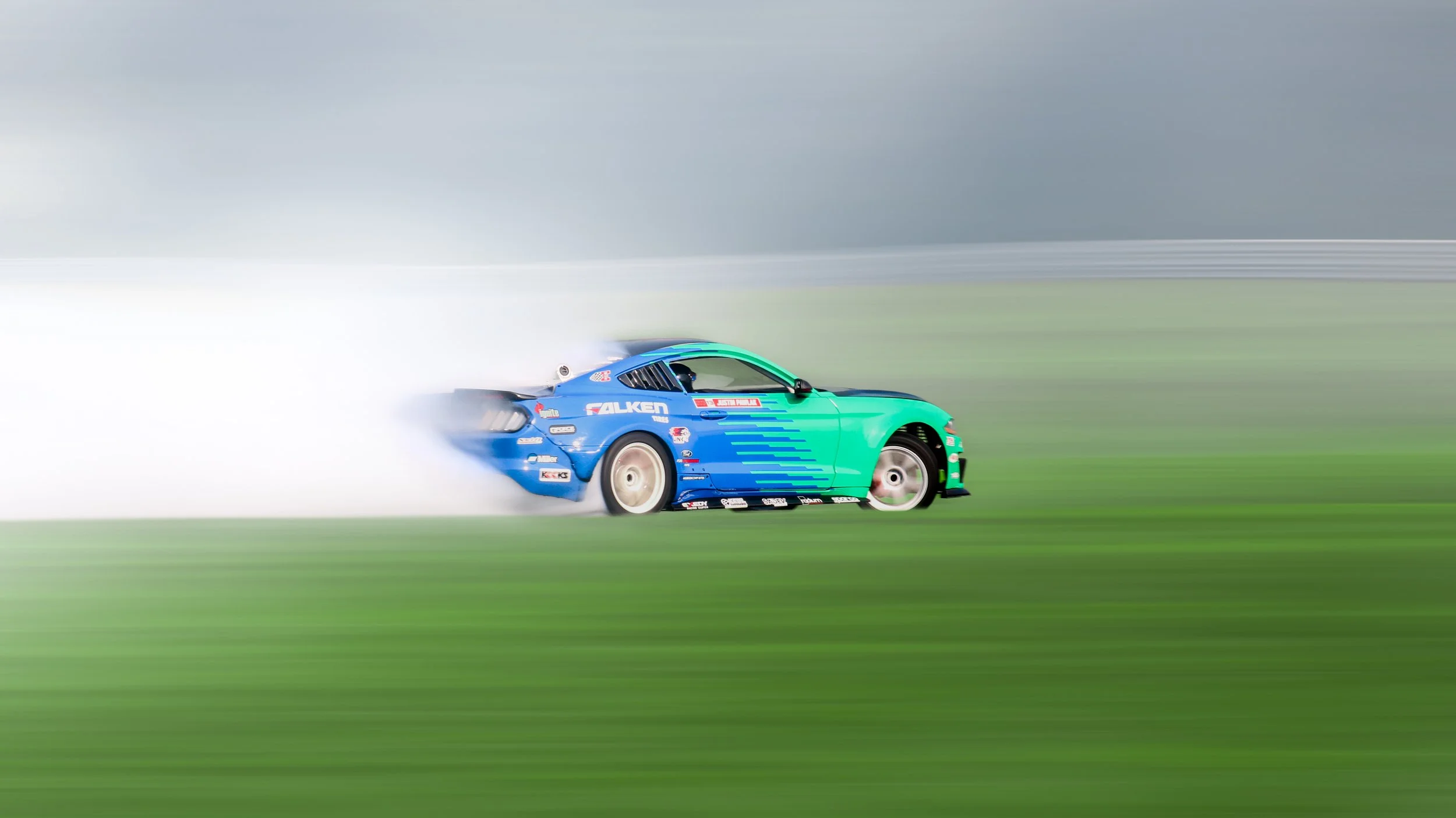 A blue and green race car speeding on a track, with motion blur effects indicating high speed.