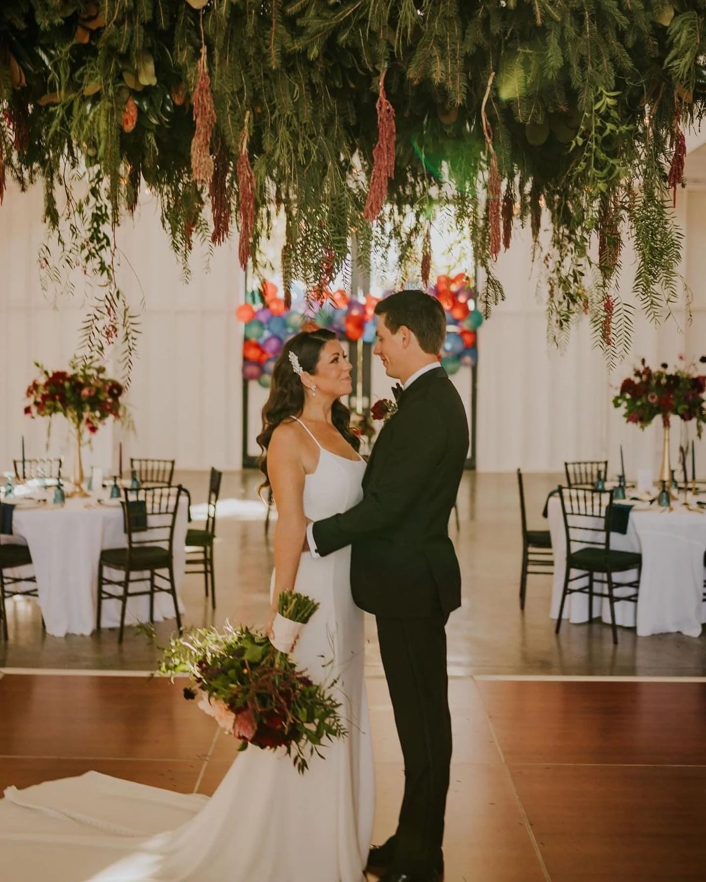 Reception décor, including floral chandelier installation, elevated centerpieces, bridal bouquet.