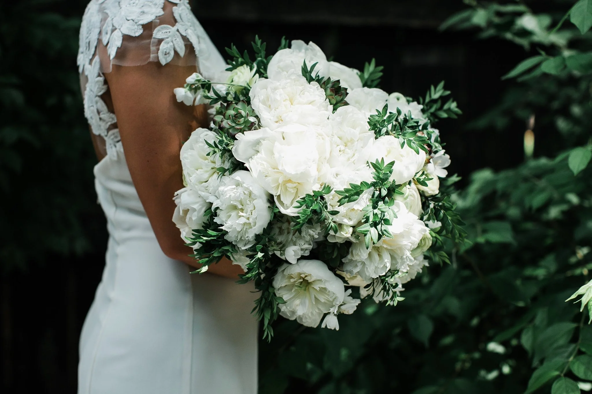 A hand tied bridal bouquet of white peonies and mixed greenery.