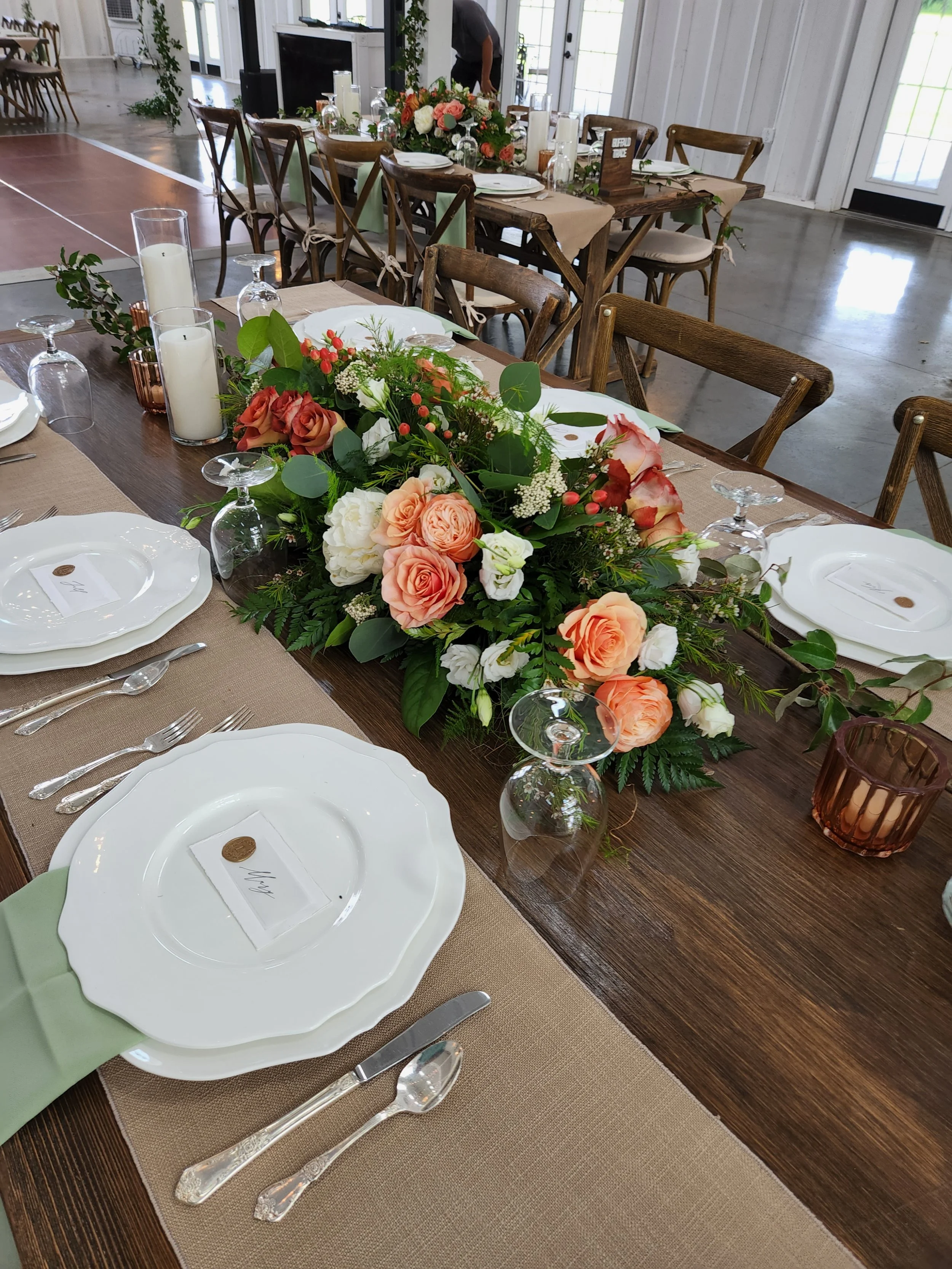 A formal dining table decorated with a floral centerpiece of roses and peonies.