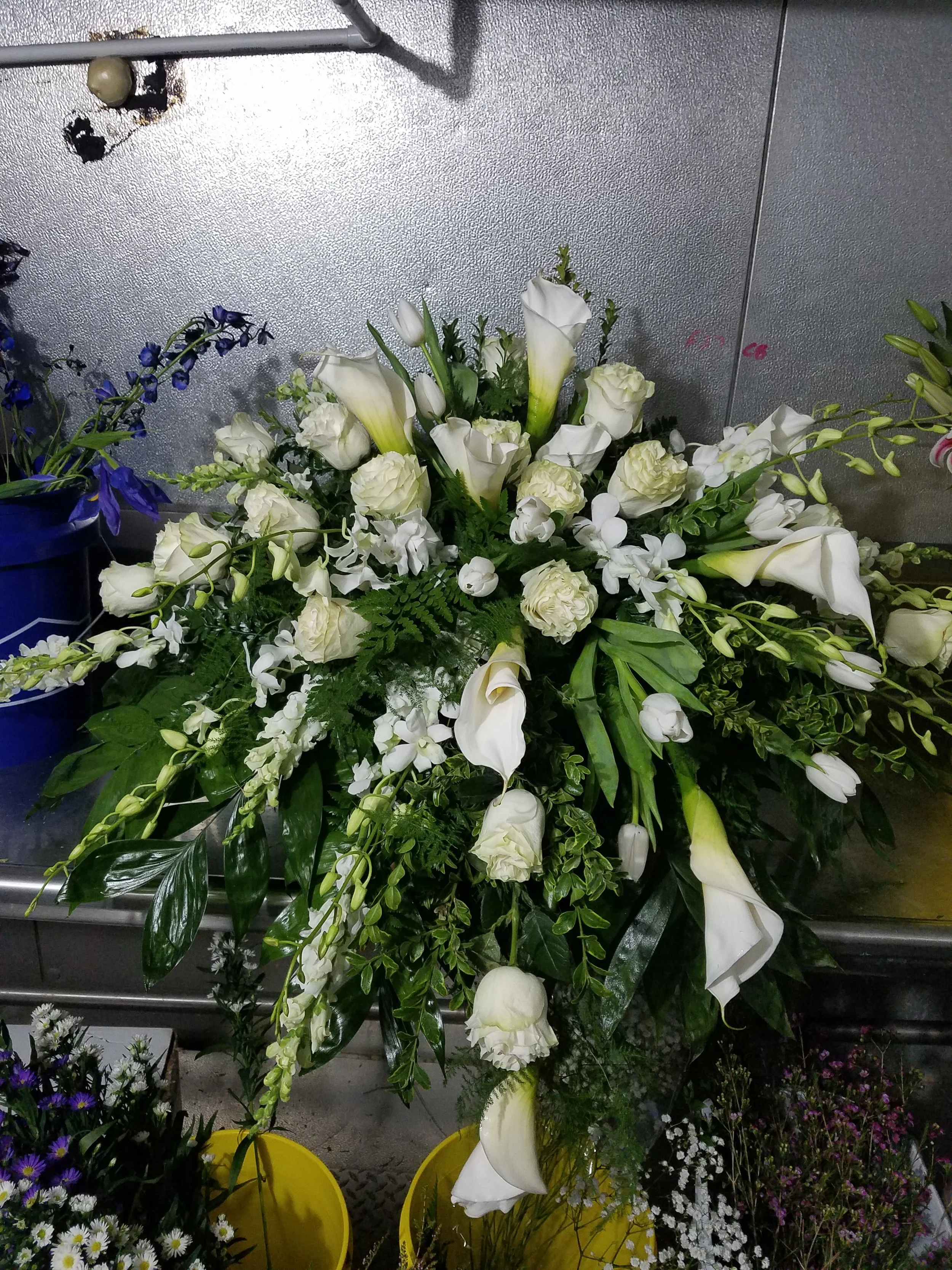 A casket spray featuring white dendrobium orchids, callas, roses and tulips.