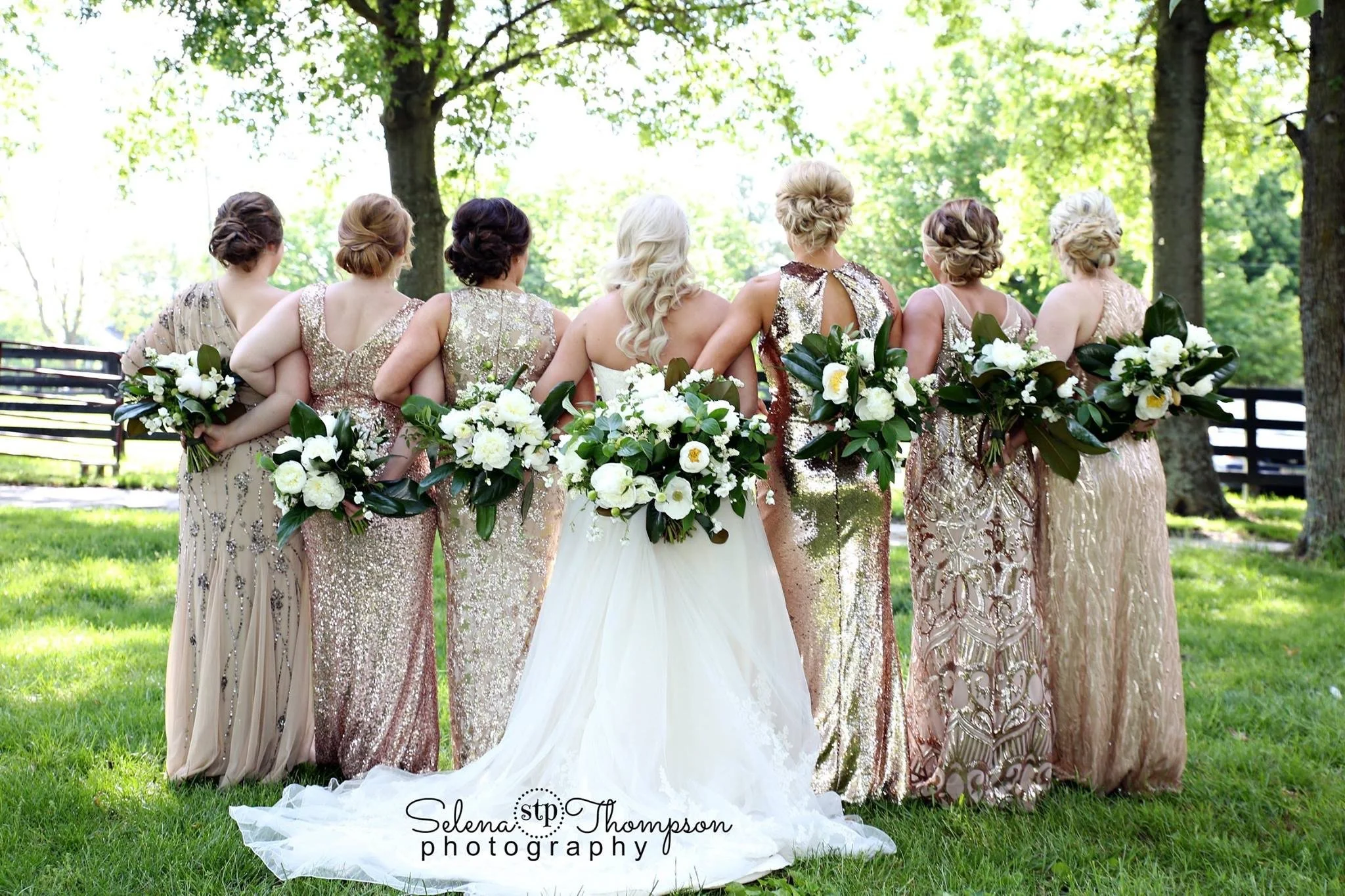 The bride is in the center, flanked by bridesmaids in gold sequin dresses, all holding large bouquets of white flowers and greenery.