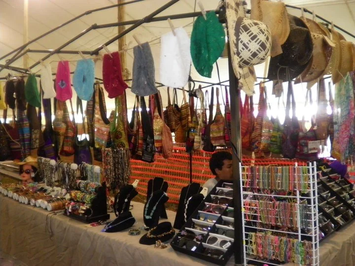 Festival or market stall selling hats, jewelry, sunglasses, and accessories.