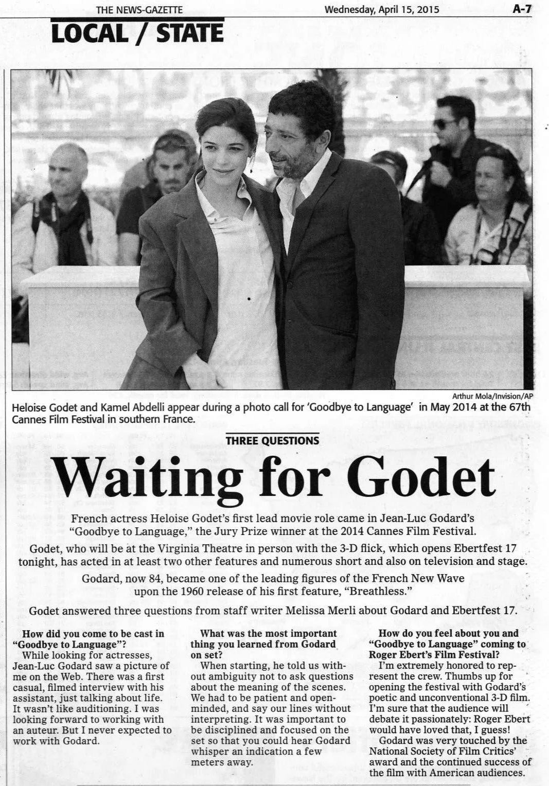 Une reproduction d'un article de journal en noir et blanc montrant Heloise Godet et Kamel Abdelli lors d'une séance photo. L'article concerne le film 'Goodbye to Language' du festival de Cannes, avec un titre principal 'Waiting for Godet' et une inte