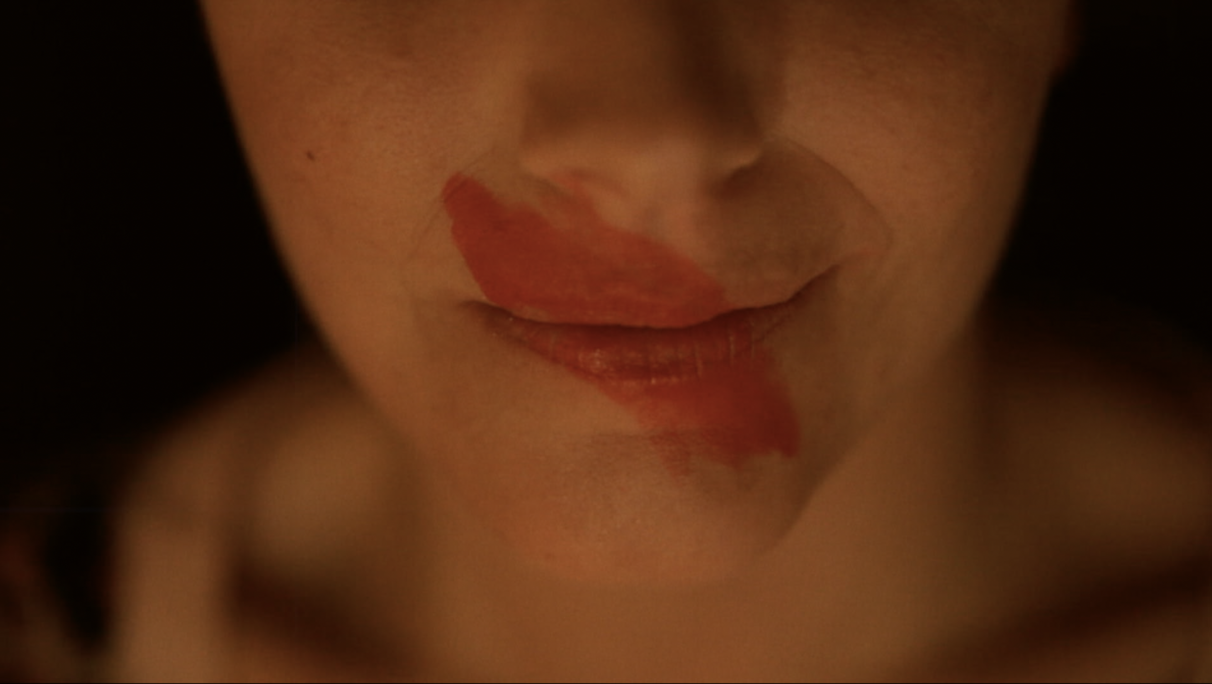 Close-up d'un visage avec des lèvres légèrement entrouvertes, certains détails du visage et des couleurs de rouge à lèvres ou taches sur les lèvres visibles.