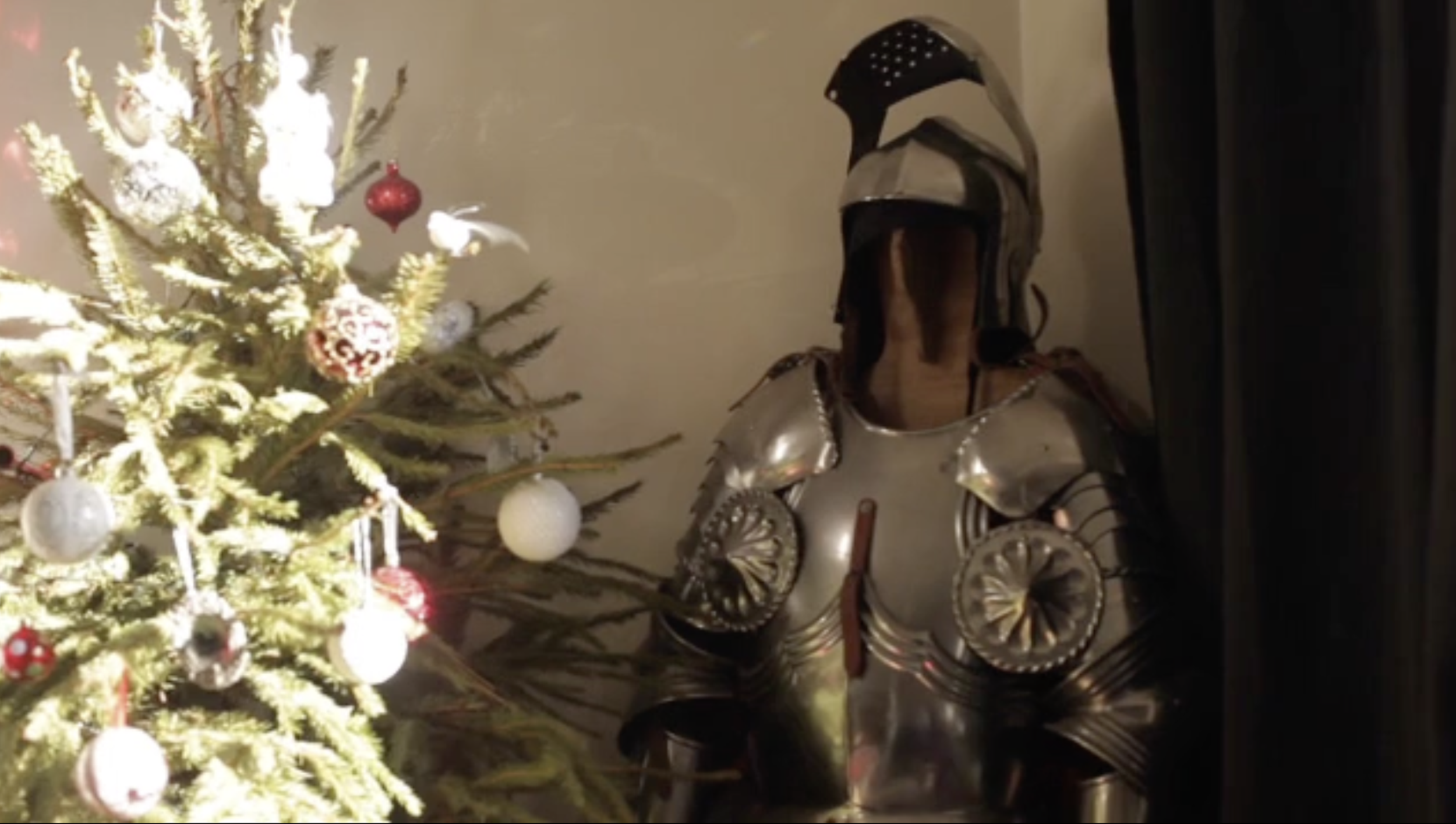 Décoration de Noël avec un arbre ornamenté et une armure de chevalier en métal