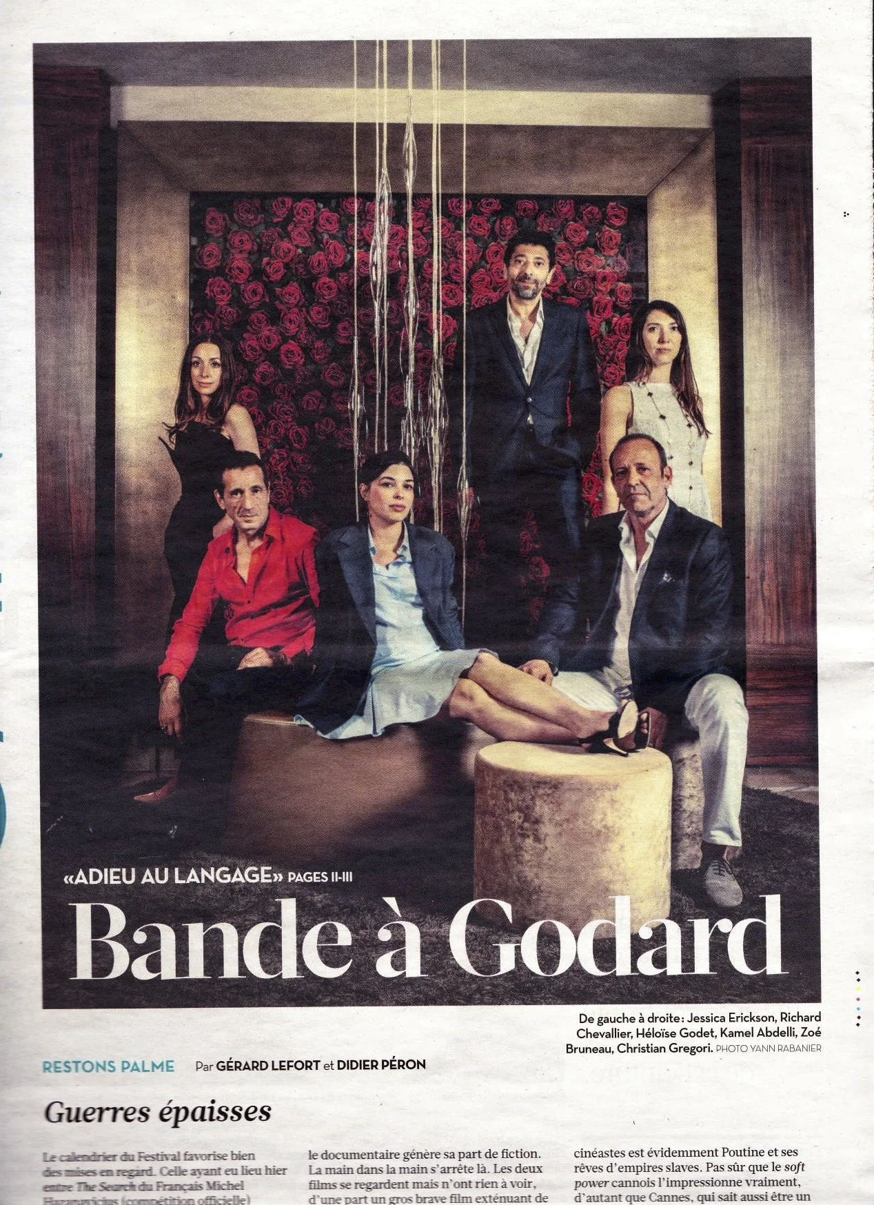 Une photo de groupe de sept personnes posant dans une pièce avec un mur de roses en arrière-plan. Il y a deux hommes et cinq femmes, certains assis, d'autres debout.