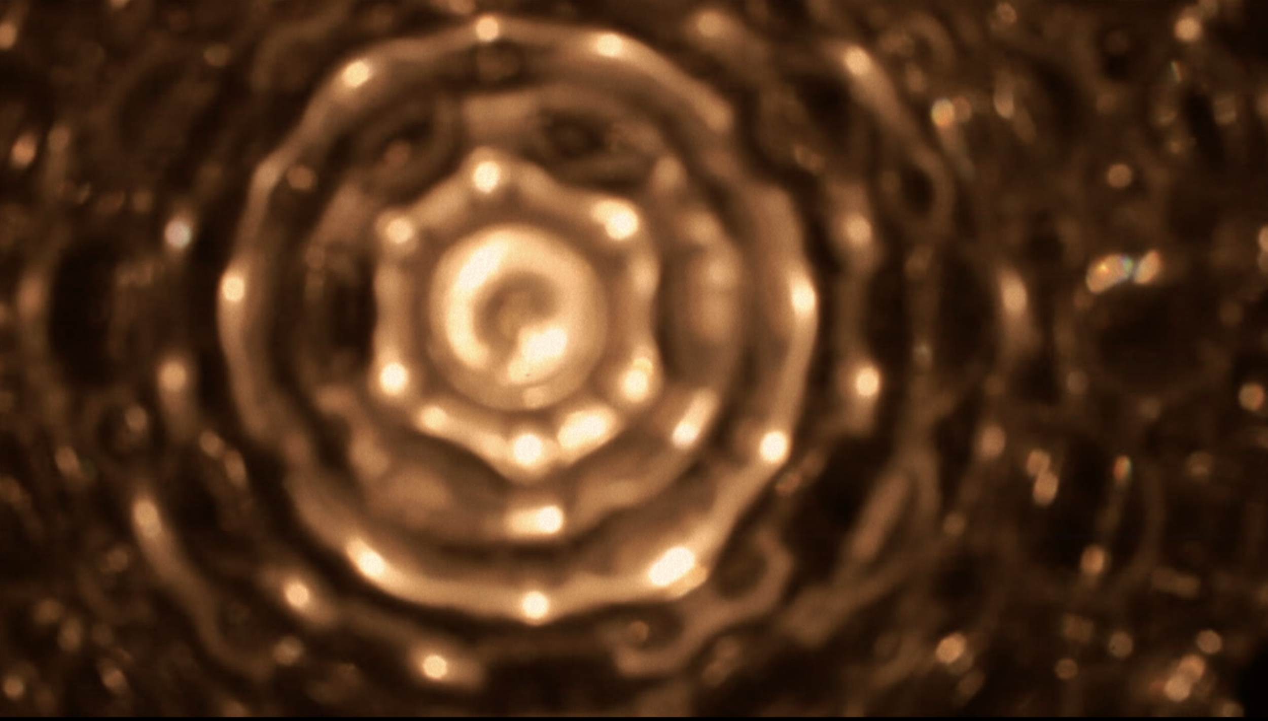 Une vue en gros plan d'une surface métallique avec un motif en spirale ou en cercles concentriques, reflétant une lumière chaude.