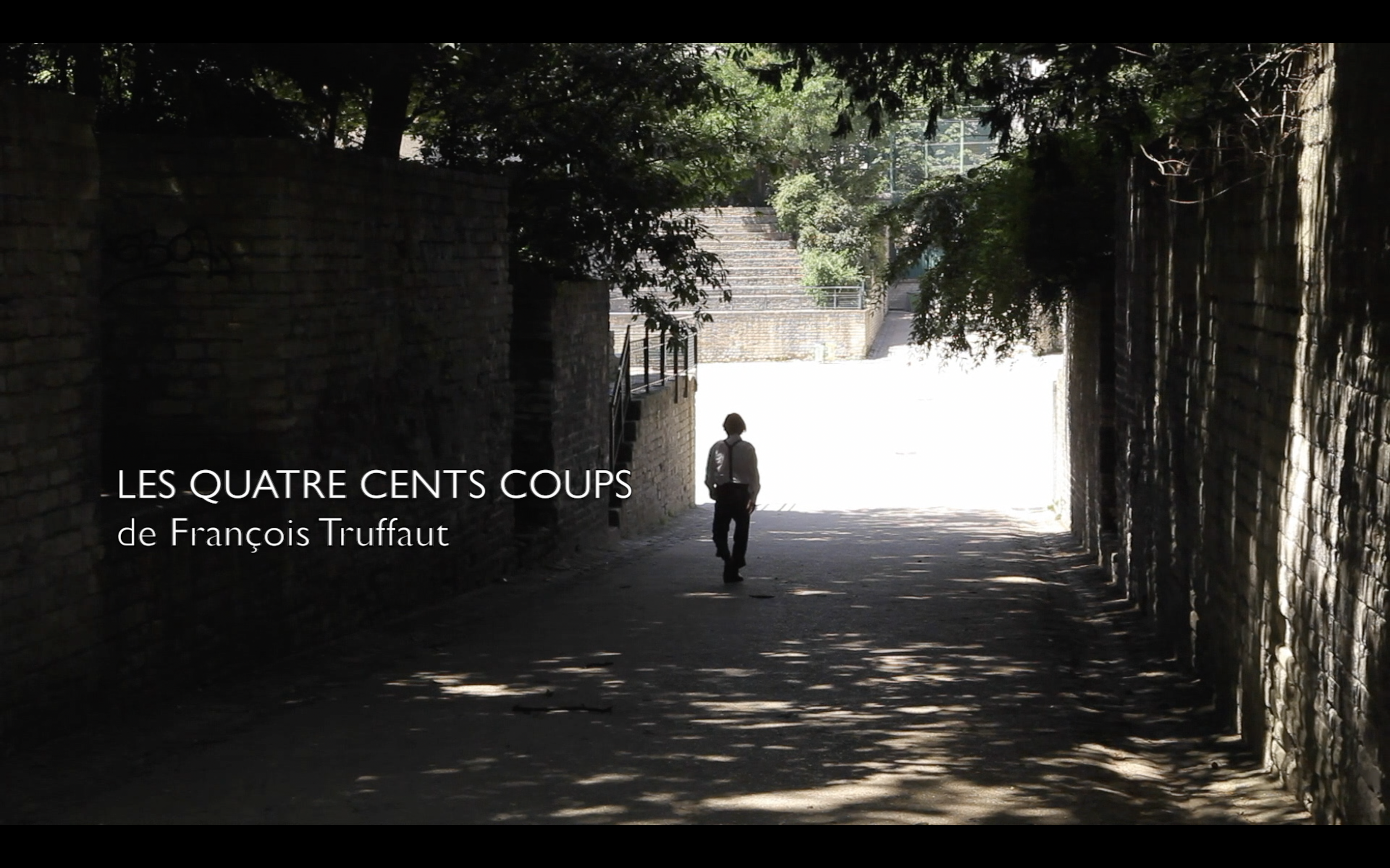 Un passage souterrain ombragé avec un homme qui marche vers la lumière, grande profondeur de champ, avec texte en français superposé indiquant "Les Quatre Cents Coups de François Truffaut".