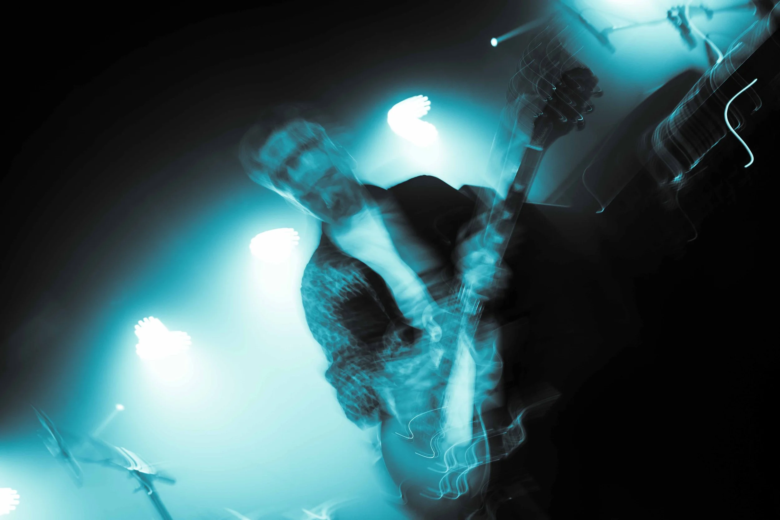 A musician playing guitar on stage with blue lighting and motion blur effects.
