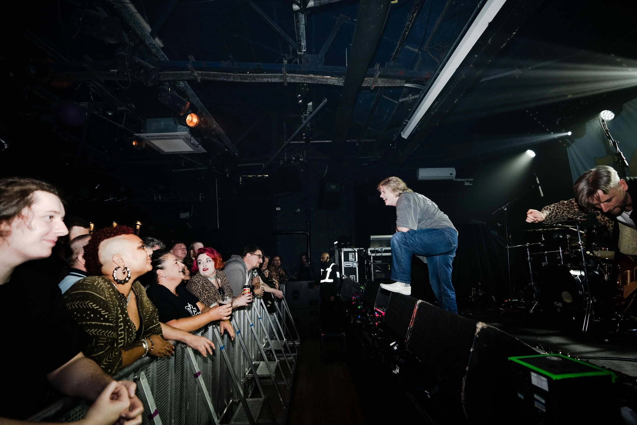 Musicians performing on stage in front of an audience at a concert, with fans enjoying the show.