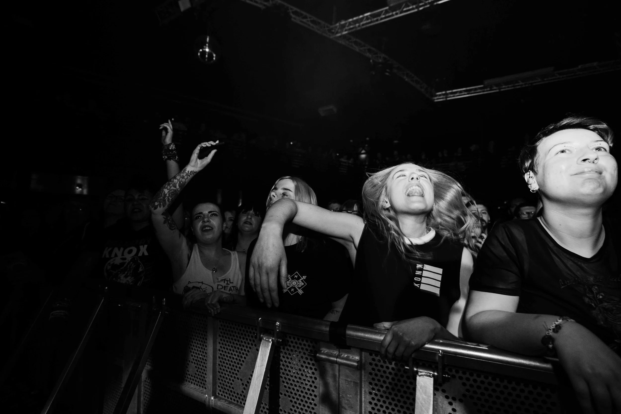 People at a concert, close to the stage, showing various expressions of enjoyment and engagement.