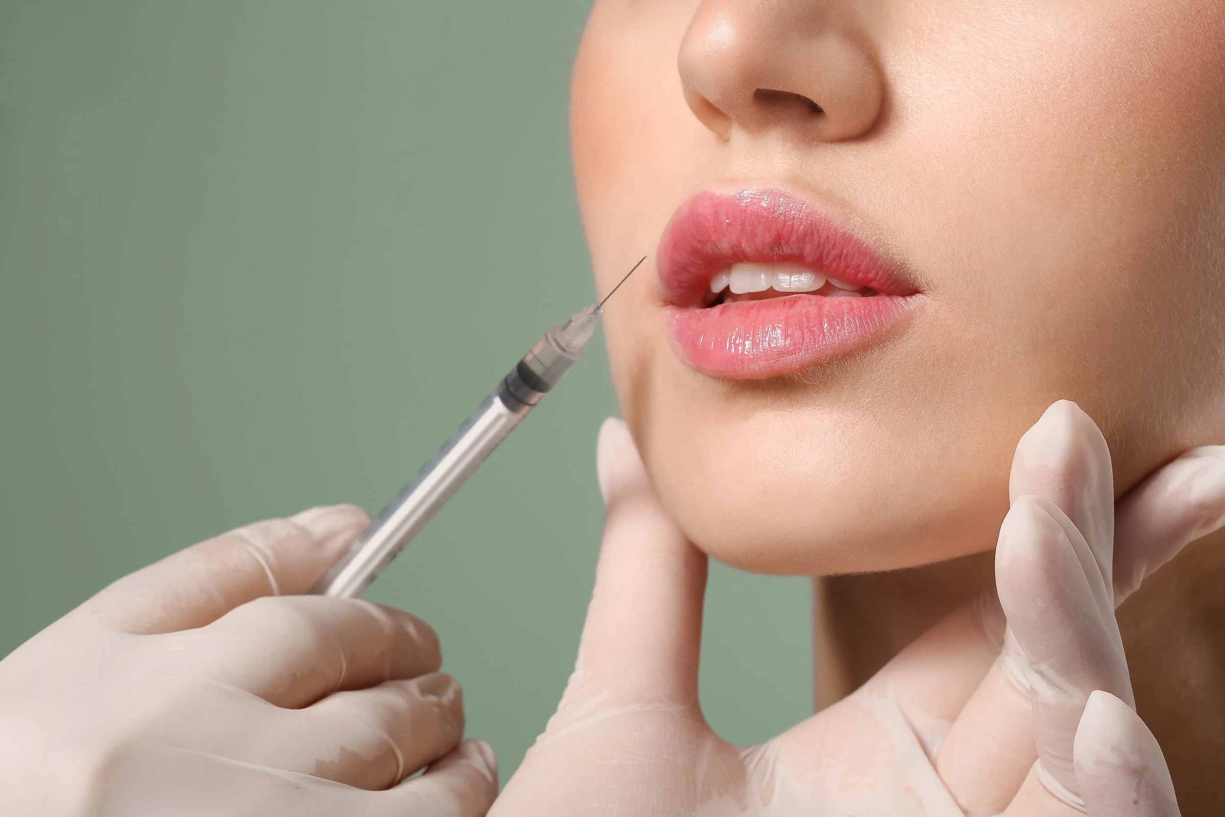 A person receiving a cosmetic injection in their lip, administered by a medical professional wearing gloves.