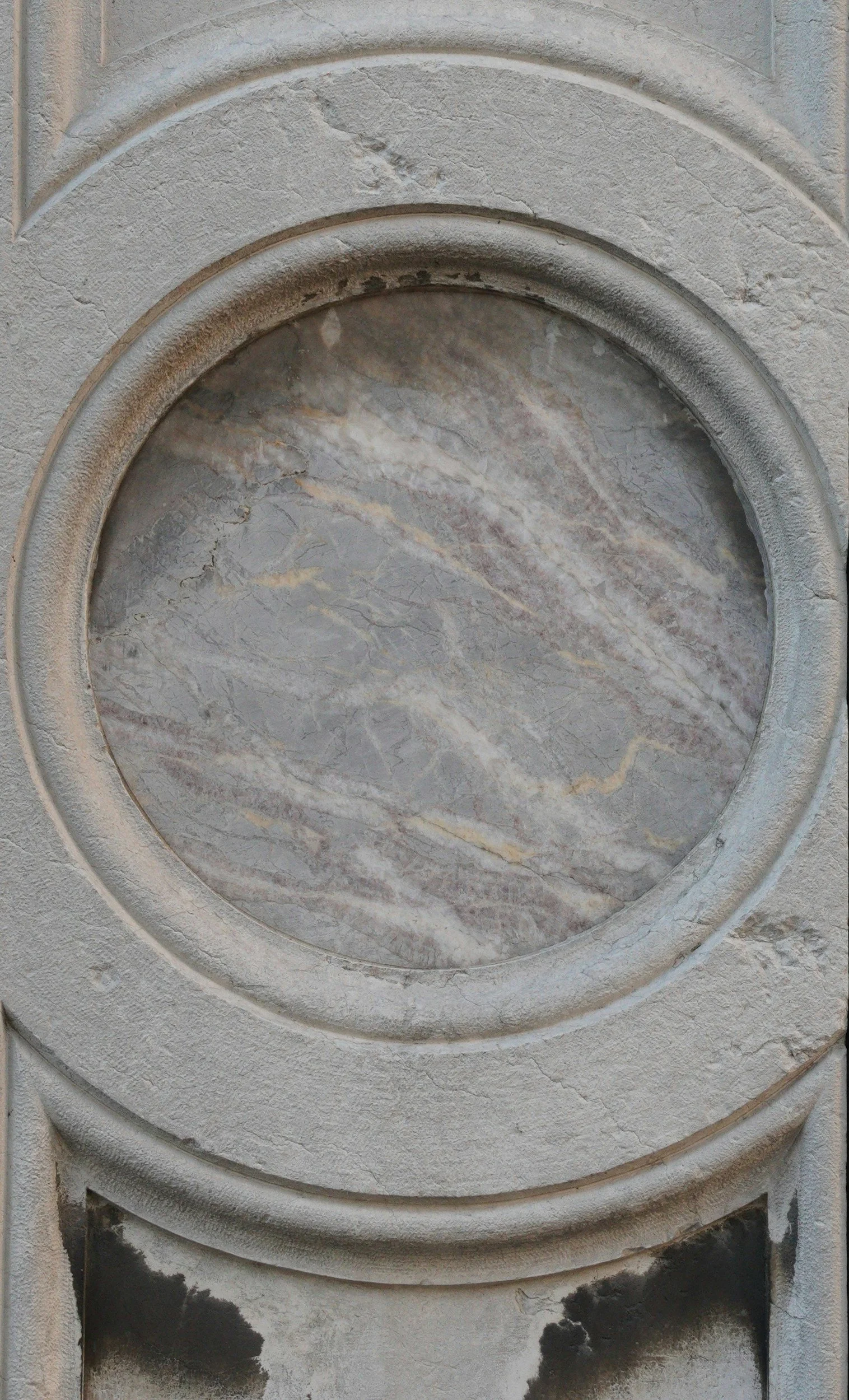 Superficie in pietra con un foro rotondo centrale, circondata da un bordo in pietra, parte di una superficie di marmo e pietra.