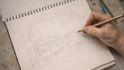 Una mano che disegna un paesaggio su un taccuino con matita