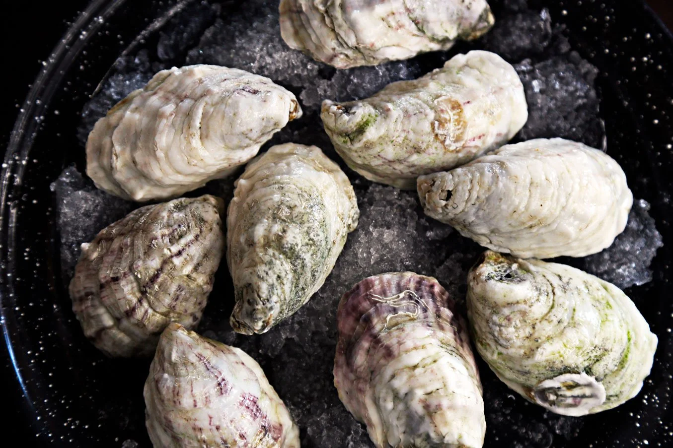 Oysters being cooked in a black frying pan.