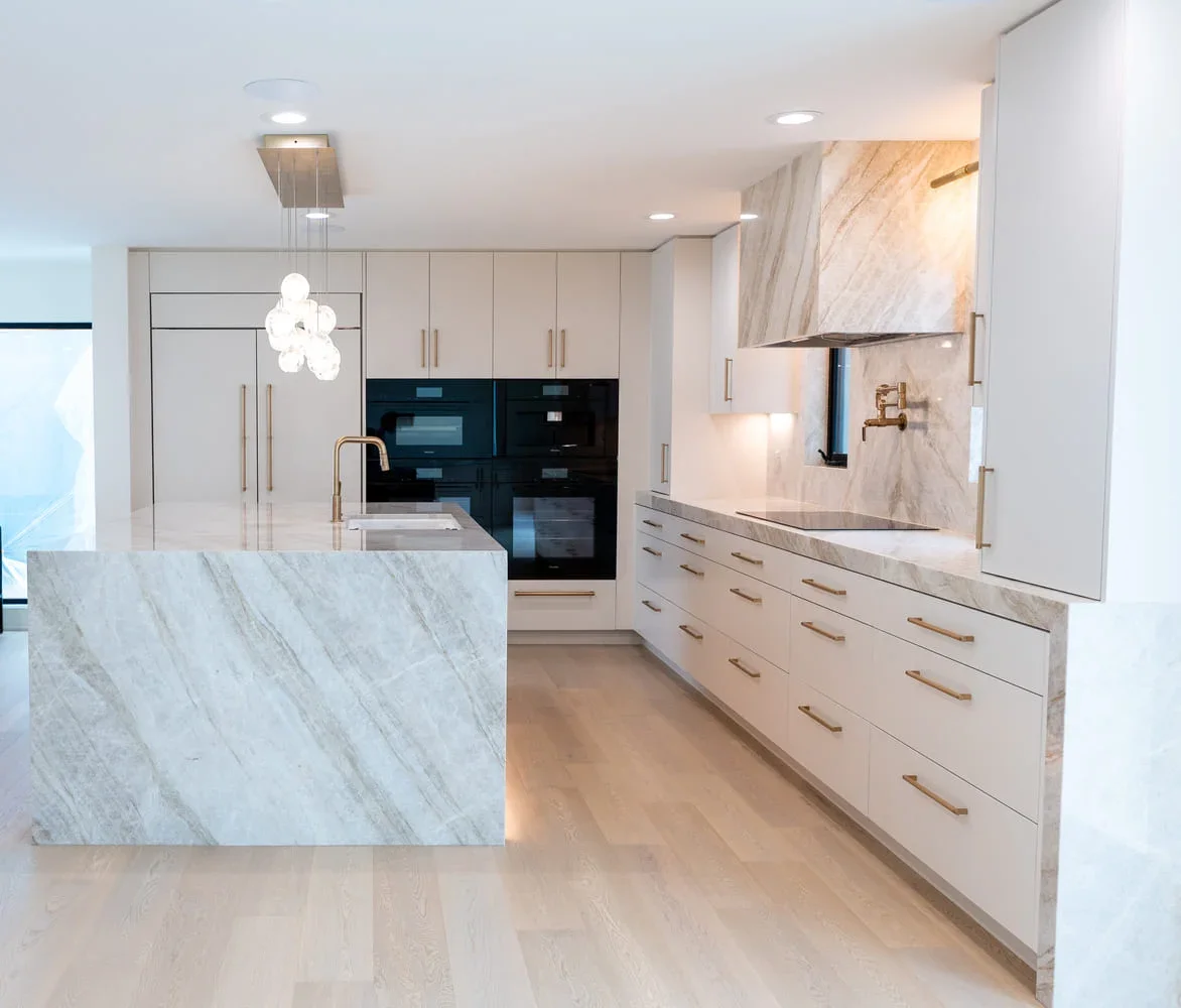 Luxury custom kitchen designed by NM Designs featuring integrated appliances, marble slab backsplash, warm brass fixtures, custom cabinetry, and thoughtfully layered finishes for a timeless remodel and elevated Orange County living.