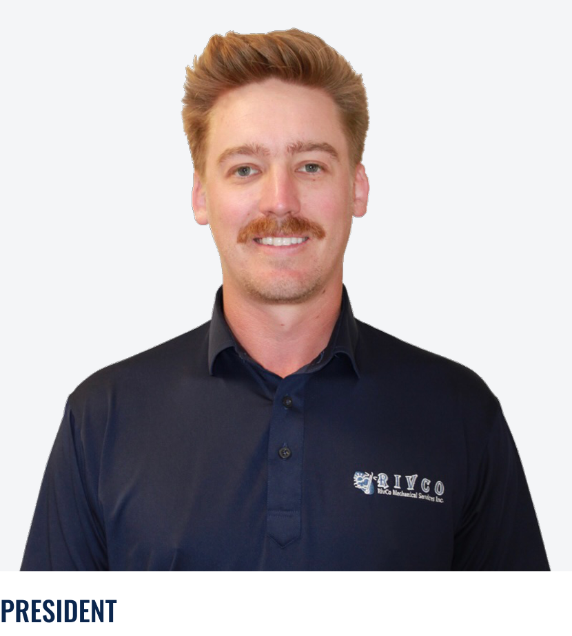 A man with light skin, red hair, and a mustache, wearing a dark blue collared shirt with the RIVCO logo, smiling, in front of a plain white background.