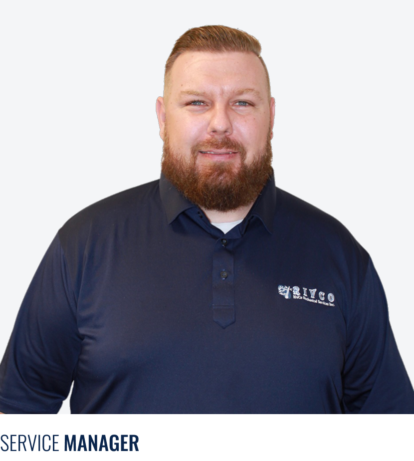 A man with a red beard and hair, wearing a navy blue polo shirt with a logo on the left chest, standing against a gray background.