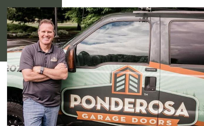 A man in a gray polo shirt and jeans standing next to a Ponderosa Garage Doors service truck, smiling with crossed arms.